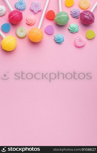 Colorful sweet lollipops and candies over pink background.  Flat lay, top view