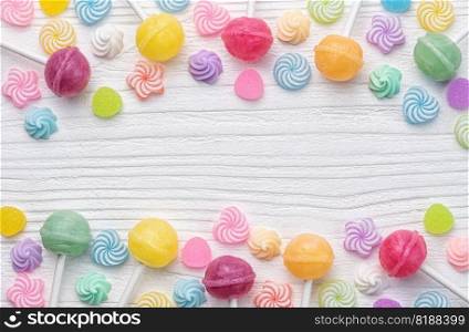Colorful sweet lollipops and candies over white wooden background.  