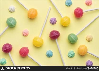 Colorful sweet lollipops and candies over yellow background.  Flat lay, top view