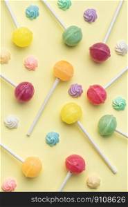 Colorful sweet lollipops and candies over yellow background.  Flat lay, top view