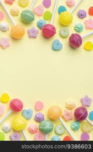 Colorful sweet lollipops and candies over yellow background.  Flat lay, top view