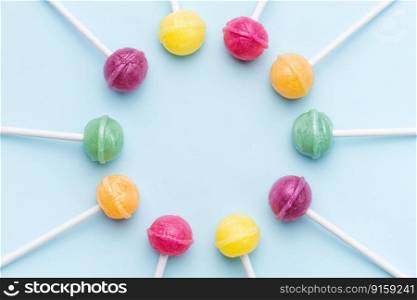 Colorful sweet lollipops over blue background.  Flat lay, top view