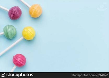 Colorful sweet lollipops over blue background.  Flat lay, top view