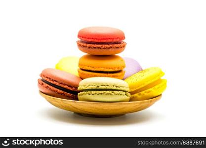 Colorful sweet macarons in wooden plate on white background