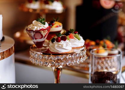 Colorful table with sweets and goodies for the wedding party reception, decoration dessert table. Delicious sweets on candy buffet. Dessert table for a party. cakes, cupcakes. Colorful table with sweets and goodies for the wedding party reception, decoration dessert table. Delicious sweets on candy buffet. Dessert table for a party. cakes, cupcakes. selective focus