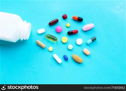 Colorful tablets with capsules and pills on blue background. Copy space