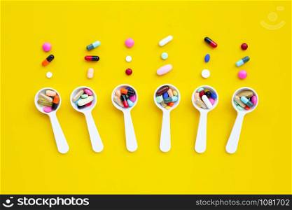 Colorful tablets with capsules and pills on yellow background. Top view