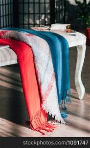 Colorful textile scarves on a fine bench, beautifully displayed for customers attraction in show-room. Fashionable, trendy, seasonal everyday essential item. Image for catalogue, booklet, market place