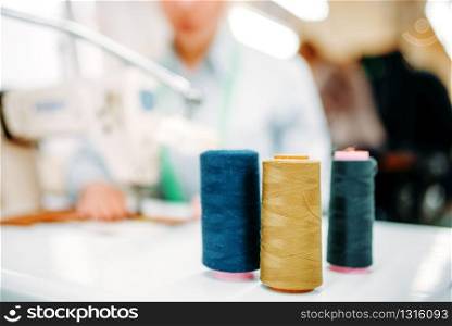 Colorful threads on spools closeup, dressmaking, sewing material, yarn on bobbins macro view, tailor on blur background