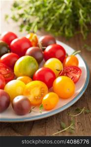 colorful tomatoes in plate on wooden background