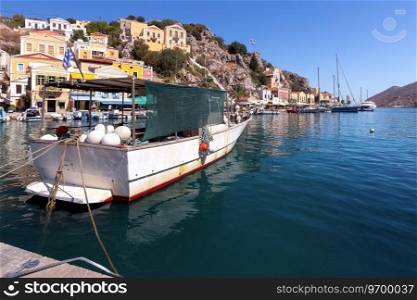 Colorful traditional fishing boats in the bay of Symi island on a bright sunny day. Simi. Greece.. Colorful traditional fishing boats in the bay of Symi island.