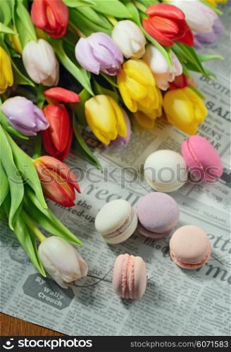 Colorful tulips and macaroons on newspaper