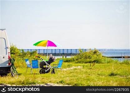 Colorful umbrella and chairs at campervan on beach. Picnic on sea shore. Caravan family vacation.. Umbrella with chairs at campervan on beach