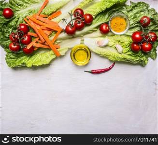 Colorful various of organic farm vegetables tomatoes on a branch, lettuce, sliced carrots, oil, seasonings border, place for text  on wooden rustic background top view vegetarian concept