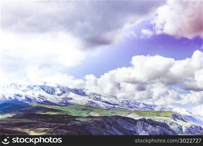 Colorful view of the mountain snow peaks under the clouds.
