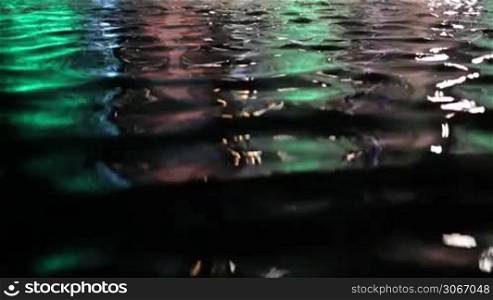 Colorful water surface with changing color. Focus turning.