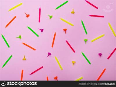 colorful wax holiday candles on a pink background, close up