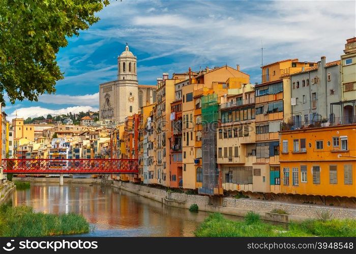 Colorful yellow and orange houses and Eiffel Bridge, Old fish stalls, reflected in water river Onyar, in Girona, Catalonia, Spain. Saint Mary Cathedral at background.