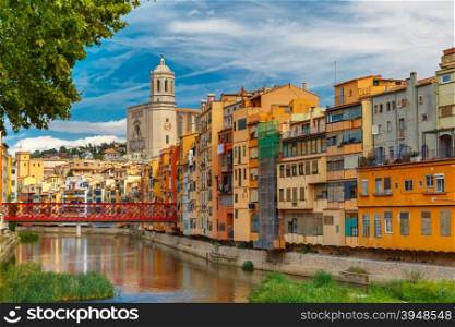 Colorful yellow and orange houses and Eiffel Bridge, Old fish stalls, reflected in water river Onyar, in Girona, Catalonia, Spain. Saint Mary Cathedral at background.