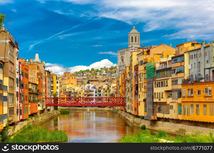 Colorful yellow and orange houses and Eiffel Bridge, Old fish stalls, reflected in water river Onyar, in Girona, Catalonia, Spain. Church of Sant Feliu and Saint Mary Cathedral at background.