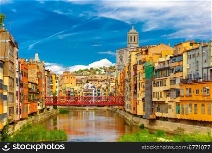 Colorful yellow and orange houses and Eiffel Bridge, Old fish stalls, reflected in water river Onyar, in Girona, Catalonia, Spain. Church of Sant Feliu and Saint Mary Cathedral at background.