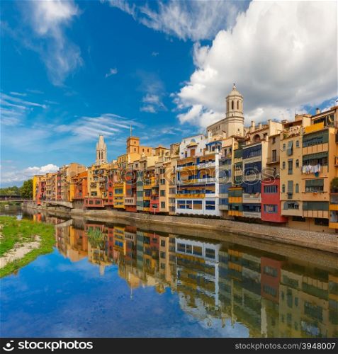 Colorful yellow and orange houses and famous house Casa Maso reflected in water river Onyar, in Girona, Catalonia, Spain. Church of Sant Feliu and Saint Mary Cathedral at background.