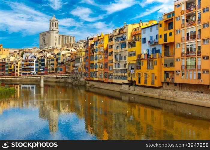 Colorful yellow, red and orange houses with the Catalan flag reflected in water river Onyar, in Girona, Catalonia, Spain. Saint Mary Cathedral at background.