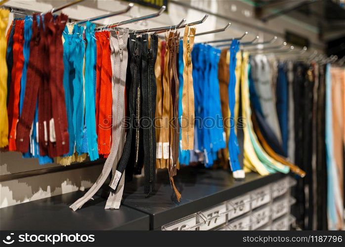 Colorful zippers on shelf in textile store, nobody. Showcase with acessories for sewing, clothing choice in shop. Colorful zippers on shelf in textile store, nobody