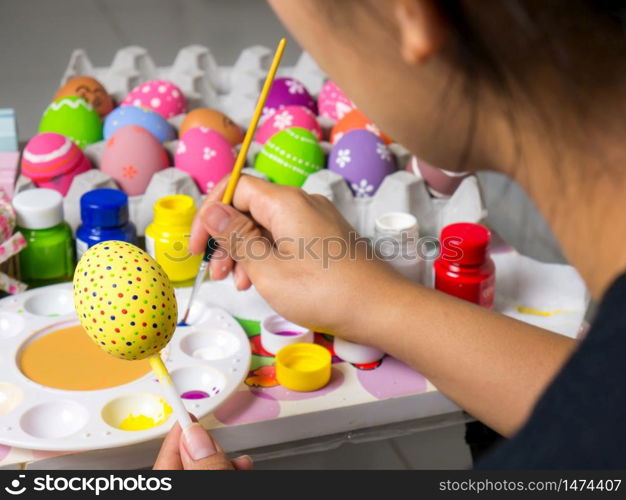 Coloring eggs with various colors beautifully with the brush during the Easter. Woman paint on easter eggs. Beautiful art on eggs in easter festival.