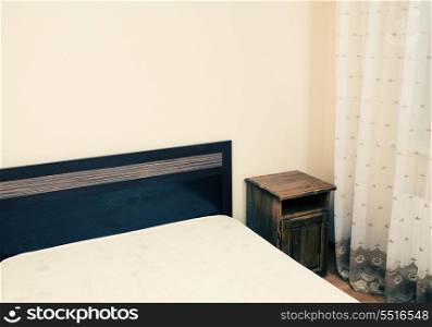 Colorized image of a part of a room with bed in a corner