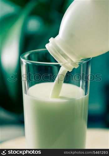 Colorized image of the milk poured in glass cup over indoors background