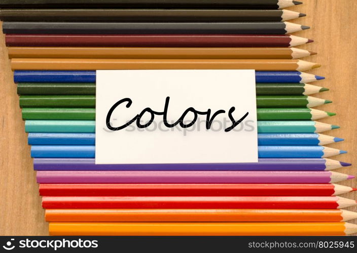 Colors text concept and colored pencil on wooden background