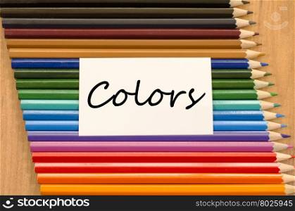 Colors text concept and colored pencil on wooden background