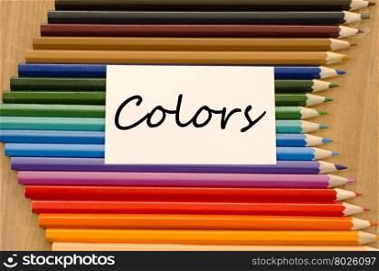 Colors text concept and colored pencil on wooden background