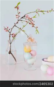 colourful easter eggs near flower twig vase with water bowl