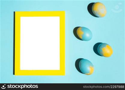 colourful easter eggs with blank frame blue table