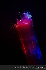 Colourful optic fibers illuminated on dark background. High speed internet concept. Data transfer optic fiber cable. Bunch of many optical fibers, glowing different colors. Technology background.