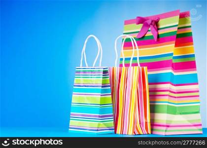 Colourful paper shopping bags against gradient background