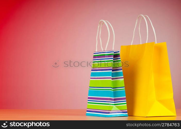 Colourful paper shopping bags against gradient background