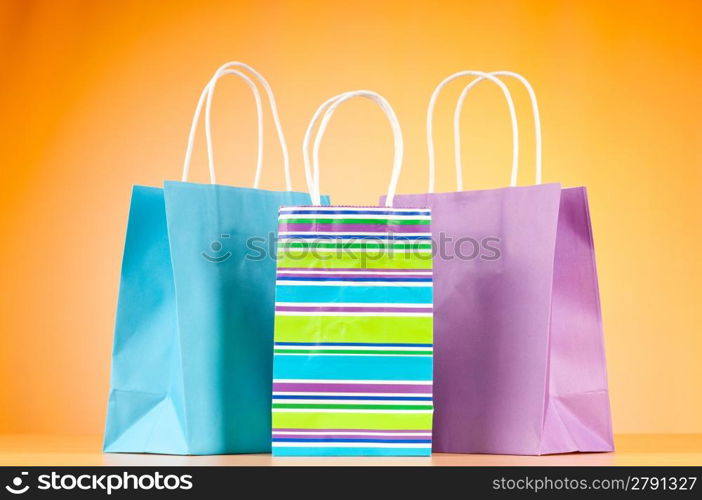 Colourful paper shopping bags against gradient background