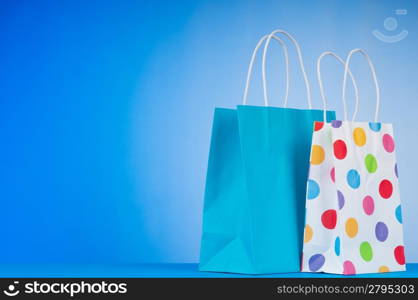 Colourful paper shopping bags against gradient background