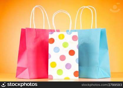 Colourful paper shopping bags against gradient background