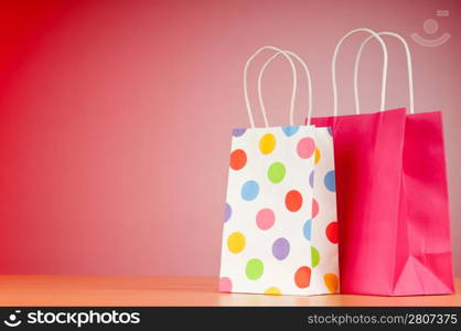 Colourful paper shopping bags against gradient background