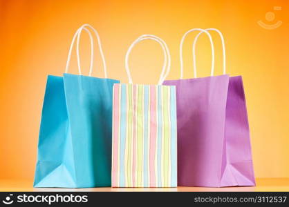 Colourful paper shopping bags against gradient background