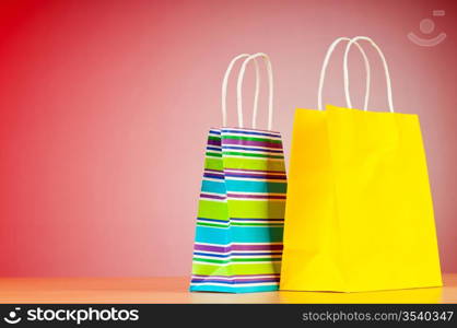 Colourful paper shopping bags against gradient background