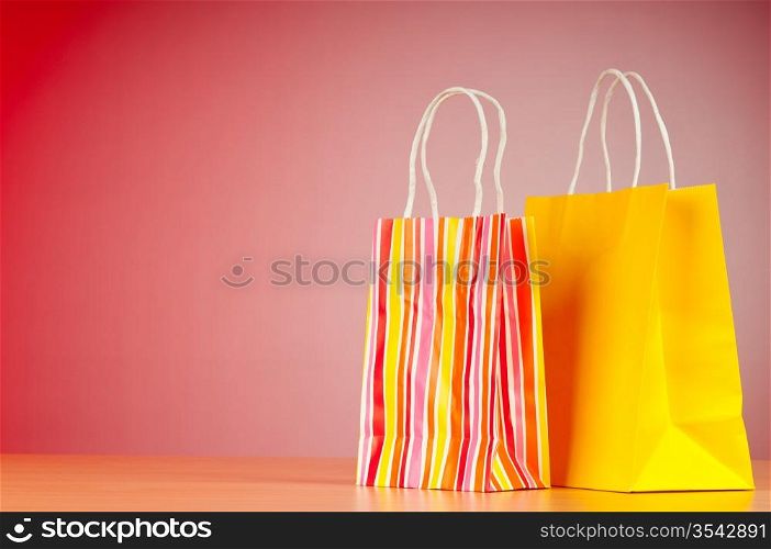 Colourful paper shopping bags against gradient background