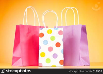 Colourful paper shopping bags against gradient background