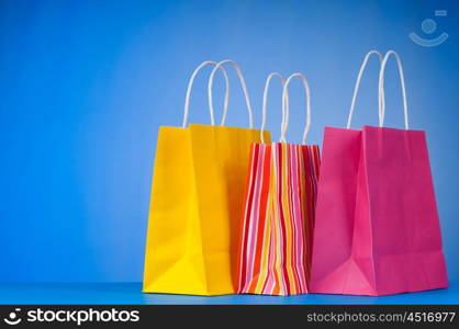 Colourful paper shopping bags against gradient background