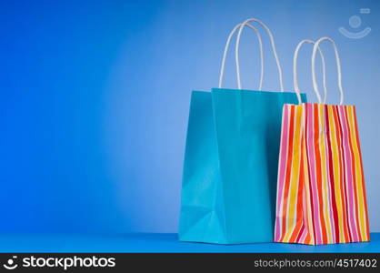 Colourful paper shopping bags against gradient background