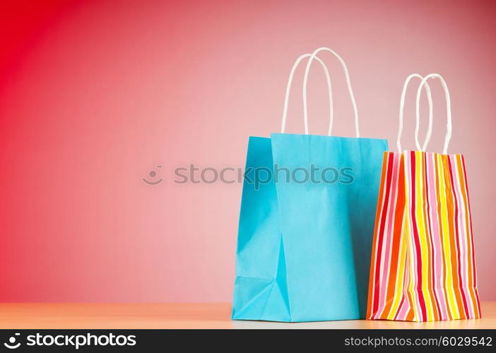 Colourful paper shopping bags against gradient background